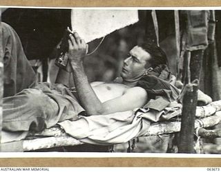 FARIA VALLEY, NEW GUINEA. 1944-01-11. QX54742 PRIVATE W. MESNER OF THE NO. 11 PLATOON, B COMPANY, 2/9TH INFANTRY BATTALION RELAXING ON HIS BUNK