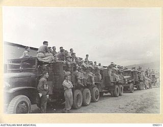 WEWAK AIRSTRIP, NEW GUINEA. 1945-09-03. PASSING TROOPS AND TRUCKS STOPPED TO VIEW THE BRIGADE PARADE OF 2/4, 2/8 AND 2/11 INFANTRY BATTALIONS HELD AT HEADQUARTERS 19 INFANTRY BRIGADE. THE PURPOSE ..