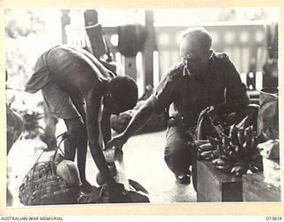 KARKAR ISLAND, NEW GUINEA. 1944-06-04. PX150 CAPTAIN R H BOYAN, AUSTRALIAN NEW GUINEA. ADMINISTRATIVE UNIT (2), EXCHANGING RICE FOR TROPICAL FRUITS WITH ONE OF THE NATIVES. TWENTY PER CENT OF THE ..