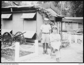 LANGEMAK BAY, NEW GUINEA. 1944-08-21. COMMANDER N.S. PIXLEY, ROYAL AUSTRALIAN NAVAL RESERVE, NAVAL OFFICER- IN- CHARGE, RAN STAFF OFFICE, WITH HIS PERSONAL SERVANT, TOMMY. NOTE THE CAPTURED ..