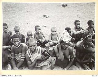 KIARIVU, NEW GUINEA, 1945-08-17. REFUGEE NATIVES LINED UP ON THE AIRSTRIP FOR COUNTING AND INSPECTION BY CAPTAIN R.R. COLE, THE ASSISTANT DISTRICT OFFICER, AUSTRALIAN NEW GUINEA ADMINISTRATIVE ..