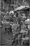 Mortuary ceremony, Omarakana: woman with crossed necklace and shaved head, carries basket that belonged to deceased man, adorned with cowry shells and other valuables