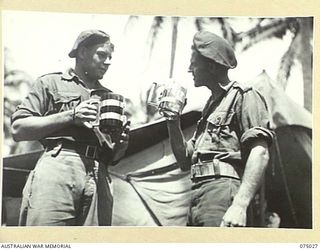 MILILAT, NEW GUINEA. 1944-08-02. QX58476 SIGNALLER T.R. COBURN (1) AND QX54142 SIGNALLER E.J. MILLS (2) HEADQUARTERS, 5TH DIVISION, PROUDLY DISPLAY THEIR HOME-MADE BEER MUGS WHILE WAITING FOR THE ..