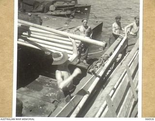 LAE, NEW GUINEA. 1944-06-14/02. TROOPS OF THE 12TH WATER TRANSPORT OPERATING COMPANY, UNLOADING IRRIGATION PIPES AT LAE FOR AN AUSTRALIAN FARM UNIT AT WAU