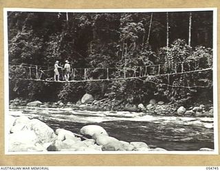 BULLDOG ROAD, NEW GUINEA, 1943-07-10. AUSTRALIAN TROOPS ON NATIVE SUSPENSION BRIDGE ACROSS THE ELOA RIVER AT THE 9 MILE POINT