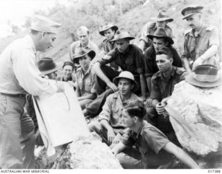 New Guinea. 1944-07-07. US Army Captain L. B. Finkelstein gives an open-air lecture on strategy to a mixed group of Australians and Americans