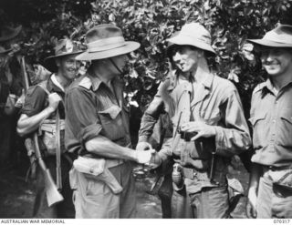 YUAT RIVER, YAGOMAI, NEW GUINEA. 1944-02-10. NX110380 BRIGADIER C.E. CAMERON, COMMANDER 8TH AUSTRALIAN INFANTRY BRIGADE, SHAKES HANDS WITH PRIVATE C. MOE, OF THE UNITED STATES, WHO WAS THE FIRST ..