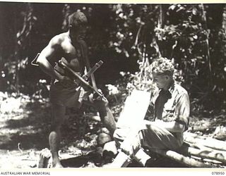 OIVA RIVER, NEW BRITAIN. 1945-02-07. SERGEANT WAI, B COMPANY, 1ST NEW GUINEA INFANTRY BATTALION ADMIRING A SKETCH OF HIMSELF DONE BY VX109068 SERGEANT D.L. BELCHER