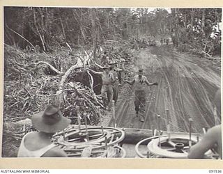 BOUGAINVILLE. 1945-05-02. SIGNALMEN OF 4 LINE SECTION, B CORPS SIGNALS LAYING OUT COPPER SIGNAL WIRE FROM REELS IN THE BACK OF A 3 TONNER ALONG THE MOTUPENA POINT - TOKO ROAD ABOUT A MILE AND A ..