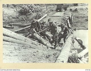 HANSA BAY, NEW GUINEA. 1944-06-20. TROOPS OF THE 4TH INFANTRY BATTALION CARRY THEIR CAPTURED JAPANESE HAND CART AS THEY CROSS THE AWAR RIVER VIA A LOT BRIDGE WHICH WAS BLOWN UP BY THE RETREATING ..