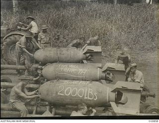 KIRIWINA, TROBRIAND ISLANDS, PAPUA. C. 1943-11. ARMOURERS OF NO. 8 (BEAUFORT) SQUADRON RAAF FITTING FINS AND NOSE CAPS TO 2000LB BOMBS TO BE DROPPED BY BEAUFORT BOMBER AIRCRAFT DURING A NIGHT RAID ..