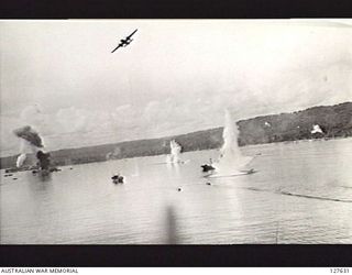 WEWAK, NEW GUINEA. 1944. B25 BOMBER AIRCRAFT OF FIFTH AIR FORCE, UNITED STATES ARMY AIR FORCE, ATTACKING SHIPPING. NOTE ONE THROUGH SMOKE FROM BURNING SHIP NEAR TOWNSHIP