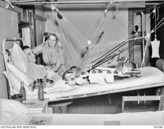 BAULKHAM HILLS, NSW. 1944-03-23. NF466276 PRIVATE O. BRADLEY, AN AUSTRALIAN ARMY MEDICAL WOMEN'S SERVICE MEMBER OF THE STAFF OF THE 103RD GENERAL HOSPITAL ADJUSTING THE PILLOWS FOR NX49126 PRIVATE ..