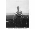Unidentified man holding a fish on a ship, Marshall Islands, 1947