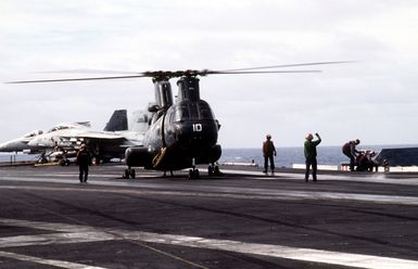 A US Navy CH-46 Sea Knight helicopter is signaled to hold by a flight deck crewman as the purple-shirted refueling team of USS KITTY HAWK (CV-63) readies the refueling hose. The KITTY HAWK is operating off the coast of Guam as part of the exercise