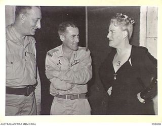LAE AREA, NEW GUINEA. 1945-08-18. GRACIE FIELDS (3), MAJOR COLLINS, DRAFT CONDUCTING OFFICER FOR THE TOUR (1) AND FLYING OFFICER N. PROPERJOHN, PILOT OF THE AIRCRAFT (2), DURING THE CONCERT AT LAE ..