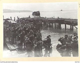 WEWAK AREA, NEW GUINEA. 1945-05-30. A LANDING BARGE COMES ASHORE ALONGSIDE THE OLD LANDING WHARF ON THE BEACH, CARRYING 3 BASE TROOPS FROM THE SS TAROONA. THE SHIP, FORMERLY OF THE INTERSTATE ..