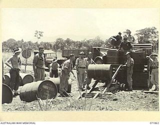 LAE, NEW GUINEA. 1944-03-30. VX111261 LIEUTENANT R. J. HARVERSON (5), WITH PERSONNEL AT THE 54TH BULK ISSUE PETROL AND OIL DEPOT PLATOON DURING THE LOADING OF A TRUCK WITH 44 GALLON DRUMS OF PETROL ..