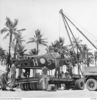 MOMOTE, LOS NEGROS ISLAND, ADMIRALTY ISLANDS. C. 1944-04. AN AIRCRAFT, CODE NAME SV-H, OF NO. 76 (KITTYHAWK) SQUADRON RAAF IS LOADED ONTO A TRUCK WHERE IT WILL BE TAKEN TO A REPAIR AND SALVAGE ..