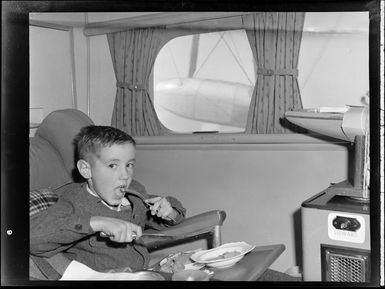 Interior shot of aircraft, includes unidentified child eating meal on Tasman Empire Airways air boat RMA New Zealand ZK-AME flight to Fiji