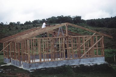 SENIOR CHIEF Builder (BUCS) Jeffrey Gilbert assist his shipmates as they measure and cut lengths of wood during the construction of an new barracks on the Seabee compound