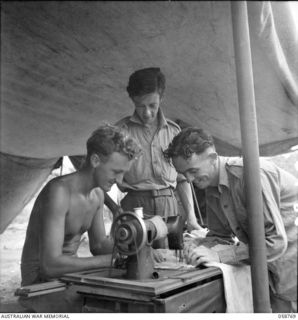 POMPOM VALLEY, NEW GUINEA. 1943-10-26. MEMBERS OF THE 7TH AUSTRALIAN DIVISION CONCERT PARTY SEWING COSTUMES FOR A NEW ACT. VX17148 CORPORAL (CPL) R. A. CUTTS (TENOR VOCALIST); NX24550 PRIVATE D. W. ..