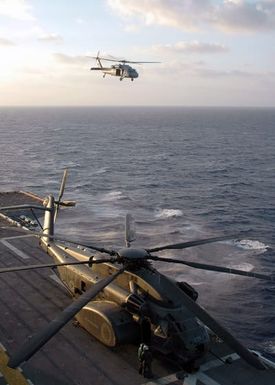 A U.S. Navy MH-60S Seahawk helicopter performs flight operations off the starboard side of the Tarawa Class Amphibious Assault Ship USS SAIPAN (LHA 2) during operations in the Mediterranean Sea on Aug. 31, 2006. In the foreground are Sailors working on an MH-53E Sea Dragon helicopter from Helicopter Mine Countermeasures Squadron Squadron 15. SAIPAN is currently underway on a routine deployment in support of the Global War On Terrorism. U.S. Navy photo by Mass Communication SPECIALIST SEAMAN Patrick W. Mullen III (Released)