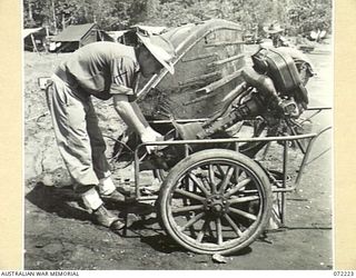 KILIGIA BEACH, NEW GUINEA. 1944-04-09. QX50132 LIEUTENANT A. ROGERS, OFFICER- IN- CHARGE 5TH DIVISION SALVAGE UNIT EXAMINES A TWIN CYLINDER JAPANESE OUTBOARD MOTOR FOUND IN GOOD CONDITION AT BUTU. ..