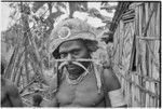 Young man wears adornments, including barkcloth cap and trade-bead necklace by Rappaport's house