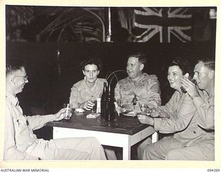 LAE AREA, NEW GUINEA. 1945-07-24. A GROUP ATTENDING A DANCE HELD BY THE STAFF OF THE AUSTRALIAN ARMY CANTEEN SERVICES, ENJOYING REFRESHMENTS. THE 2/1 GUARD REGIMENT BAND PLAYED DURING THE EVENING. ..