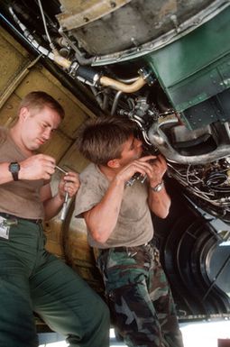 A1C Homer Shumake, left, and AIRMAN 1ST Class Terry Price, maintenance specialists with the 320th Bomb Wing repair an engine on a B-52 Stratofortress aircraft during exercise Giant Warrior '89