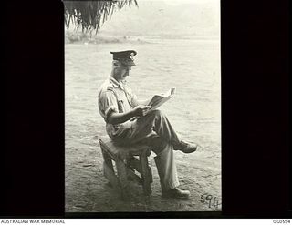 VIVIGANI, GOODENOUGH ISLAND, PAPUA. C. 1944. FLYING OFFICER TOM DAVIDSON OF MELBOURNE, VIC, A RAAF WELFARE OFFICER, IS BALANCED PRECARIOUSLY ON THIS COLLAPSIBLE UPHOLSTERED STOOL