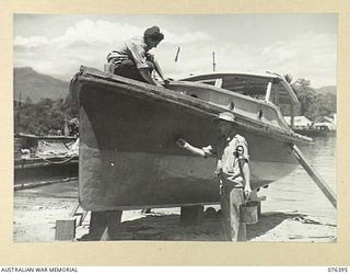 LABU, NEW GUINEA. 1944-10-03. CRAFTSMAN J.E. TAYLOR (1) AND CRAFTSMAN H.A. FINLEY (2), PAINTING OE OF THE UNIT LAUNCHES AM642 "SENORITA" AFTER THEY HAD BUILT A CABIN ON HER AT THE 1ST WATERCRAFT ..