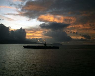 A silhouetted port beam view of the nuclear-powered aircraft carrier USS ENTERPRISE (CVN 65) as it enters Pearl Harbor