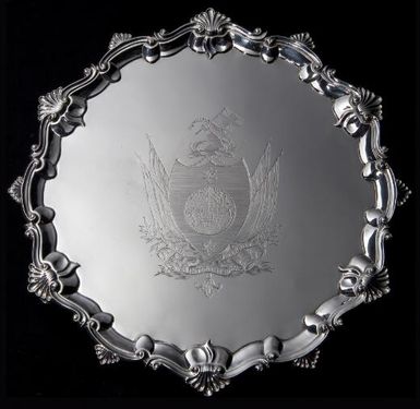 [A George III silver salver engraved with coat of arms of Captain James Cook] [incorporating a terrestrial globe centred on the Pacific Ocean between two pole stars on a shield, the crest of an arm embowed in naval uniform holding a Union flag with the motto "Circa orbem", the motto "Nil intentatem reliquit" below]