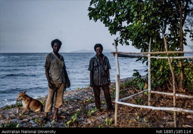 Research assistants, Linus Digim'Rina and Kevin Adiyaleyale standing on the beach near Wapolu