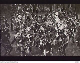 DOBODURA, NEW GUINEA. 1943-10-10. NATIVE CEREMONIAL DANCES IN PROGRESS IN THE VILLAGE CLEARING WERE ATTENDED BY ALLIED TROOPS AND NURSES