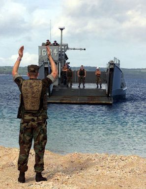 US Navy (USN) Construction Mechanic Construction Apprentice (CMCA) Michael Klinegardner, a Beach MASTER with Unit 1, guides a Landing Craft Utility (LCU) 1634 during an offload exercise at the Inner Apra Harbor on the island of Guam, in support of Exercise TANDEM THRUST 2003