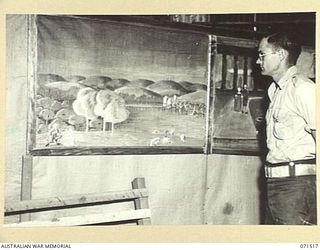 KOITAKI, PORT MORESBY AREA, PAPUA, NEW GUINEA. 1944-03-26. NX151419 PRIVATE S. R. ROSE, OF THE 113TH CONVALESCENT DEPOT VIEWING MURALS HE HAS PAINTED IN THE AUSTRALIAN ARMY EDUCATION SERVICE MUSIC ..