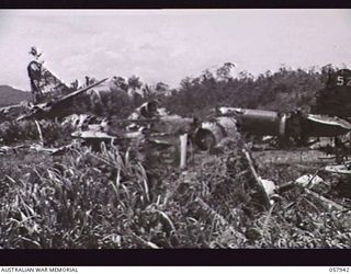 LAE, NEW GUINEA. 1943-10-04. REMAINS OF JAPANESE AIRCRAFT DESTROYED ON THE GROUND AT THE AIRSTRIP IN THE 4TH AUSTRALIAN BASE AREA. BOMBER TAIL IS ON THE RIGHT WITH "52" PAINTED ON IT. BUSHES AND ..