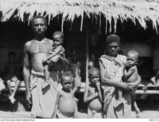 HOPOI, NEW GUINEA, 1943-10-20. GROUP PORTRAIT OF A NATIVE VILLAGE FAMILY. LEFT TO RIGHT:- AWADI, MASSAWAWI, ASSUNGWI, NGALA, ALUWI, GENOM. MESSAWAWI AND GENOM ARE "TWO-FELLER-ONE-TIME-PICCANNIES" ..