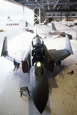 Elevated front view of an F-4 Phantom II aircraft from Marine Fighter Attack Squadron 232, parked in a maintenance hangar during Exercise OPPORTUNE JOURNEY 84