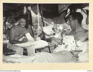 WUNUNG PLANTATION, JACQUINOT BAY, NEW BRITAIN. 1945-03-02. PATIENTS FROM THE 19TH INFANTRY BATTALION DISCUSSING THEIR CASES IN THE SURGICAL WARD OF THE 105TH CASUALTY CLEARING STATION. IDENTIFIED ..