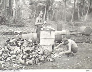 MALMAL MISSION, JACQUINOT BAY, NEW BRITAIN. 1944-11-30. PRIVATE BERE (1) AND PRIVATE D. DRAYTON (2), HEADQUARTERS, 5TH DIVISION, BURNING TINS AND OTHER KITCHEN REFUSE