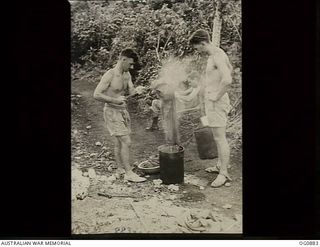 KIRIWINA, TROBRIAND ISLANDS, PAPUA. 1943-11-27. PILOT OFFICER (PO) J. HOWELL, SEMAPHORE, SA (LEFT), AND PO R. J. WALKER, CAULFIELD, VIC, WASHING THEIR CLOTHES IN AN OLD OIL DRUM FOLLOWING THE MOVE ..