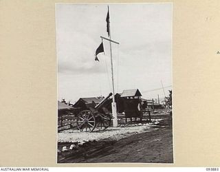 CAPE WOM, WEWAK AREA, NEW GUINEA, 1945-07-11. THE ENTRANCE TO HEADQUARTERS 6 DIVISION. IN THE FOREGROUND IS A 105 JAPANESE GUN WHICH WAS CAPTURED IN THE WEWAK AREA