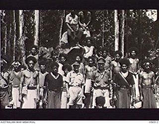 REINHOLD HIGHWAY, NEW GUINEA, 1943-08-31. AUSTRALIANS PHOTOGRAPHED WITH A GROUP OF POLICE BOYS AND BOSS BOYS, NX3046 CAPTAIN L. J. TINKER, AUSTRALIAN ARMY SERVICE CORPS (LEFT) AND WARRANT OFFICER ..