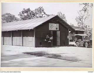 TOROKINA, BOUGAINVILLE. 1945-11-26. FRONT OF THE BUILDING AT BOSELY FIELD WHERE RADIO STATION 9AC TOROKINA, AUSTRALIAN ARMY AMENITIES SERVICE BROADCASTING STATION ON BOUGAINVILLE IS HOUSED