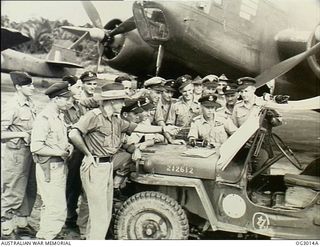 TADJI, NORTH EAST NEW GUINEA. 1945-06-27. LIEUTENANT C. C. ELING OF HURLSTONE PARK, NSW (IN SLOUCH HAT), BRIEFING TAC-R (TACTICAL RECONNAISSANCE) CREWS AT TADJI AIRSTRIP. LT ELING, AUSTRALIAN ARMY, ..