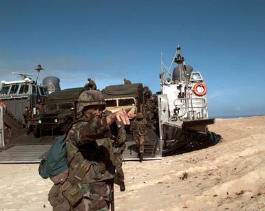 A US Marine directs mechanized traffic from a Landing Cushion Assault Craft (LCAC) during an amphibious landing. About 1,000 Marines landed on the beach as part of the RIMPAC '96 amphibious assault at Pacific Missle Range Facility, Barking Sands, Kauai, Hawaii